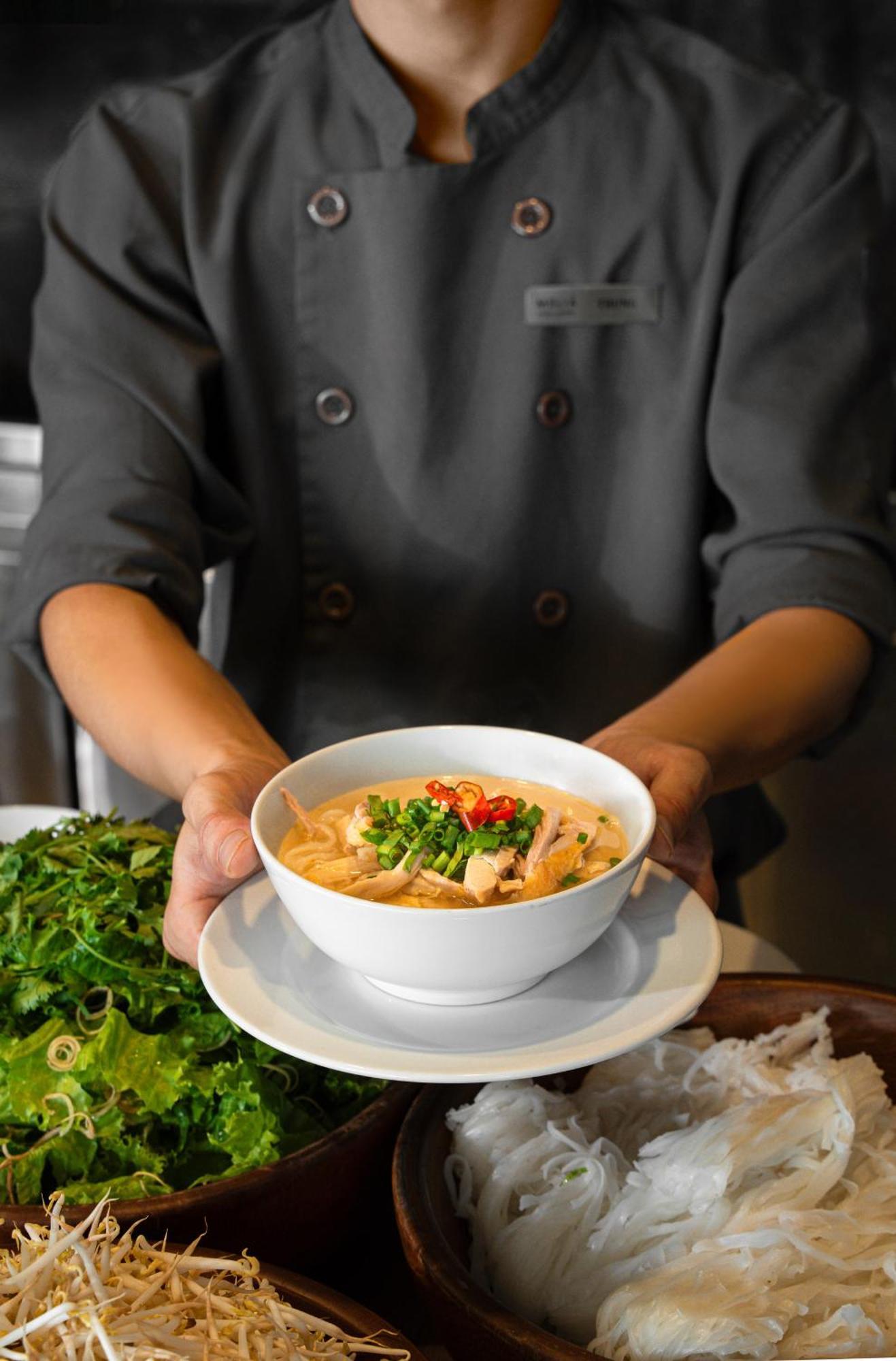 Melia Vinpearl Hue Otel Dış mekan fotoğraf A chef holding a bowl of Tom Kha soup